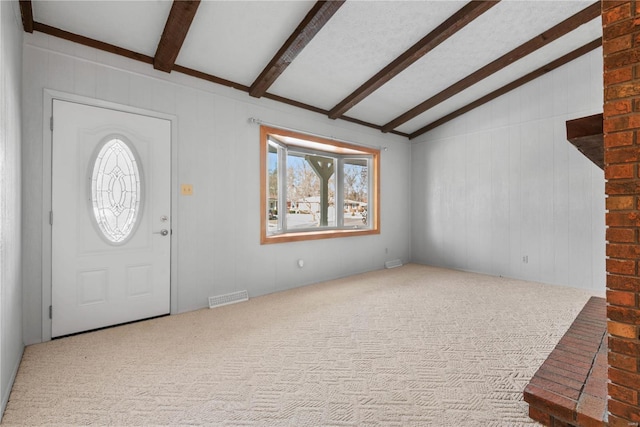 carpeted foyer featuring lofted ceiling with beams