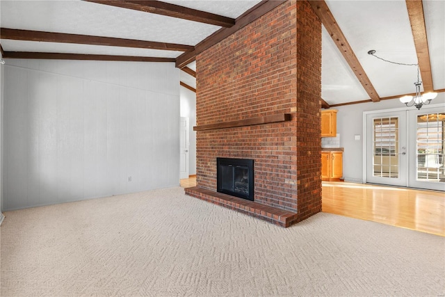 unfurnished living room with lofted ceiling with beams, carpet, a notable chandelier, and a fireplace