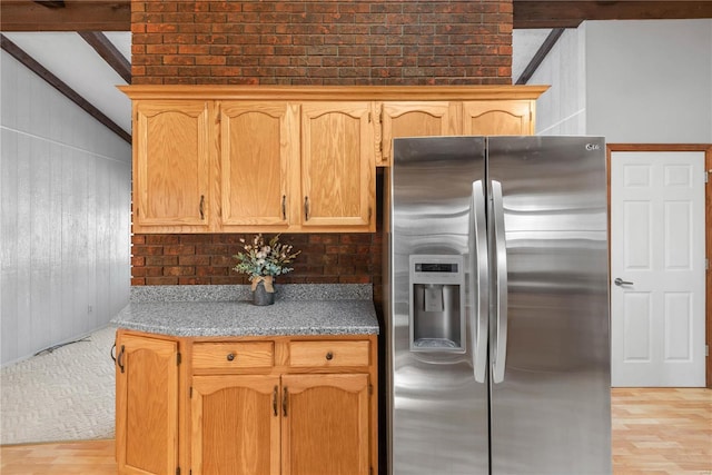 kitchen featuring stainless steel refrigerator with ice dispenser and vaulted ceiling with beams