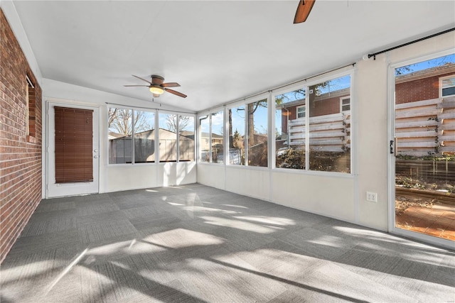 unfurnished sunroom featuring ceiling fan, a healthy amount of sunlight, and vaulted ceiling