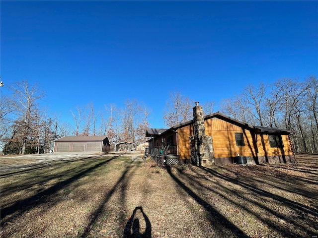 view of property exterior with an outbuilding, a yard, cooling unit, covered porch, and a garage