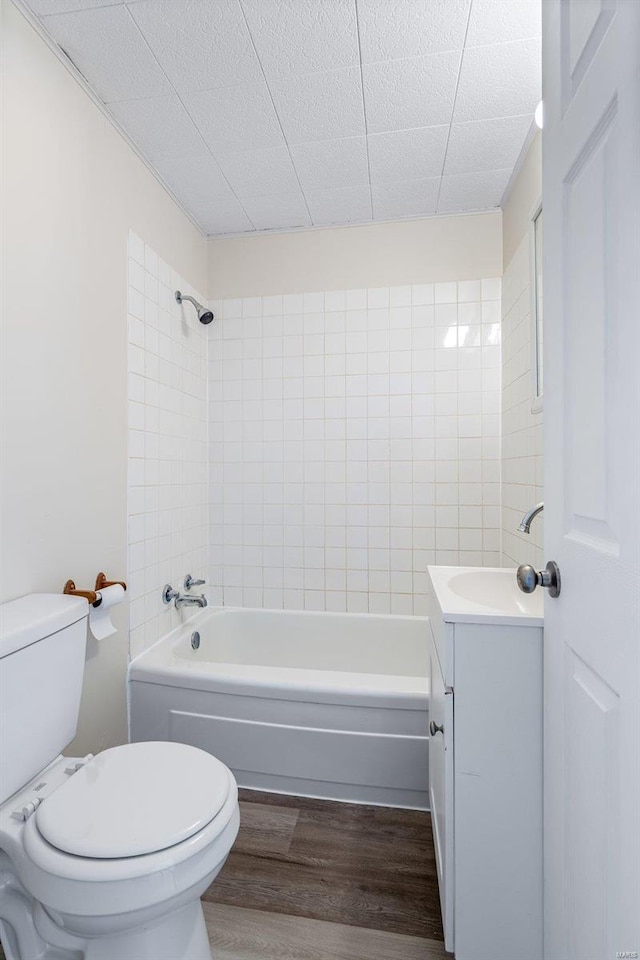 full bathroom featuring hardwood / wood-style flooring, toilet, tiled shower / bath, and vanity