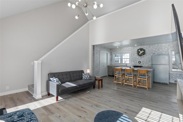 living room featuring high vaulted ceiling, light hardwood / wood-style floors, and a notable chandelier