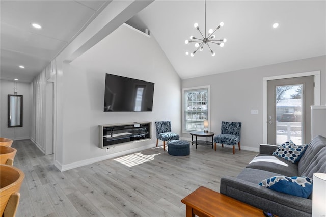 living room with light hardwood / wood-style floors, lofted ceiling, a notable chandelier, and a healthy amount of sunlight