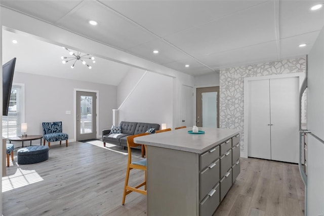 kitchen featuring gray cabinetry, light wood-type flooring, a kitchen island, a breakfast bar, and plenty of natural light