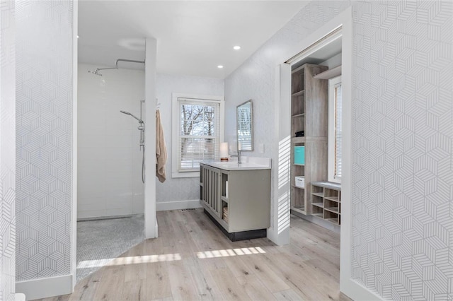 bathroom with hardwood / wood-style flooring, a shower, and vanity