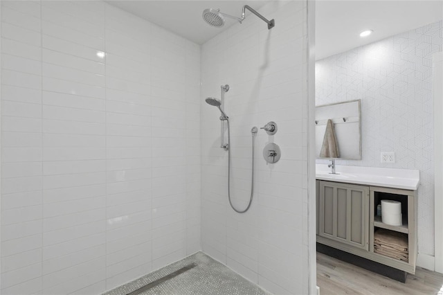 bathroom featuring wood-type flooring, tiled shower, and vanity