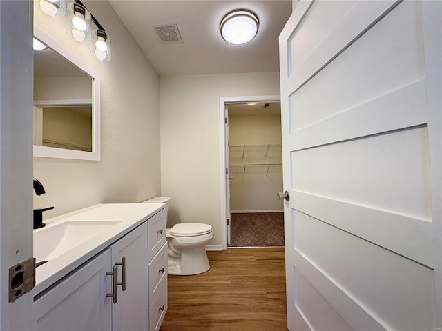 bathroom with toilet, wood-type flooring, and vanity