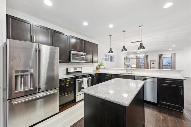 kitchen featuring a center island, hanging light fixtures, appliances with stainless steel finishes, dark hardwood / wood-style flooring, and kitchen peninsula