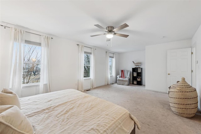 bedroom featuring ceiling fan, light colored carpet, and multiple windows