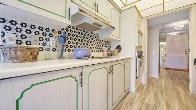 kitchen featuring tasteful backsplash, white appliances, light hardwood / wood-style floors, and cream cabinetry