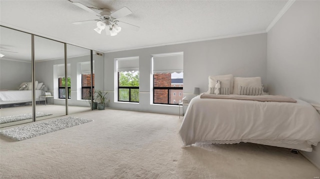 carpeted bedroom featuring ceiling fan, ornamental molding, and a closet