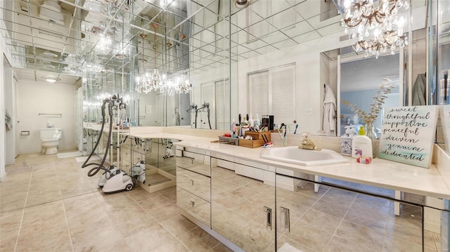 bathroom with vanity, a notable chandelier, and toilet