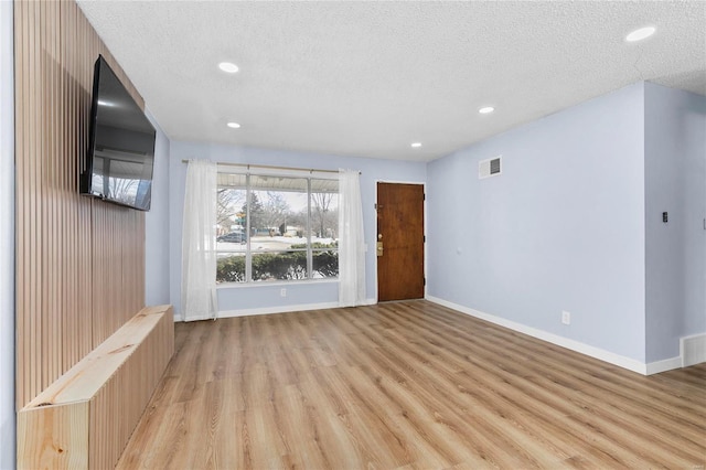 unfurnished living room with light hardwood / wood-style floors and a textured ceiling