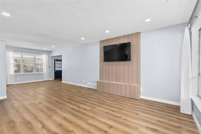 unfurnished living room featuring light hardwood / wood-style floors and a textured ceiling