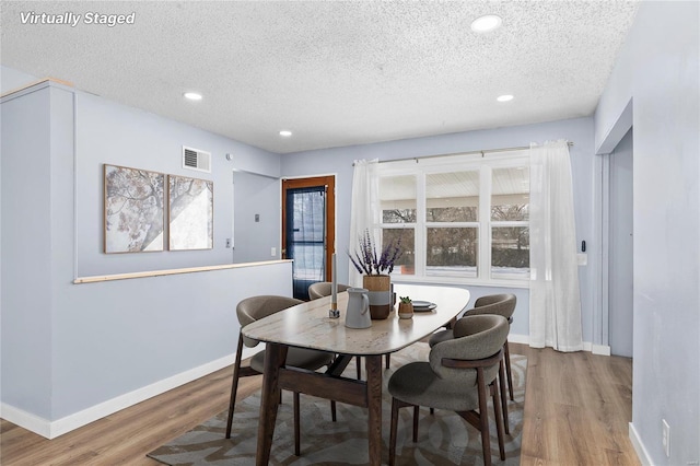 dining room featuring hardwood / wood-style flooring, a textured ceiling, and a wealth of natural light