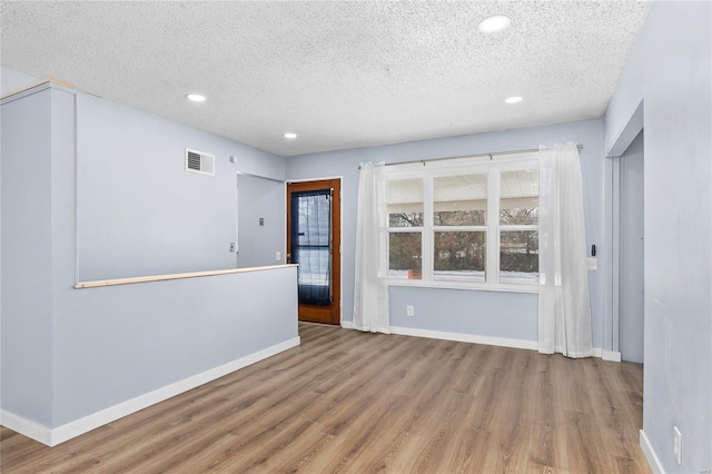 spare room with a textured ceiling and hardwood / wood-style floors