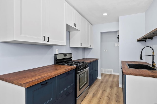 kitchen with white cabinetry, stainless steel gas range, wooden counters, and blue cabinets