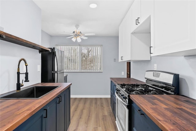 kitchen featuring sink, blue cabinets, stainless steel appliances, and wood counters