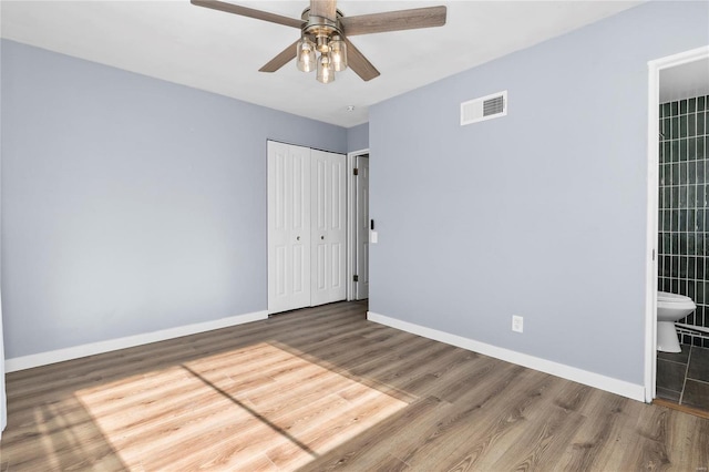 unfurnished bedroom featuring ceiling fan, connected bathroom, and hardwood / wood-style flooring