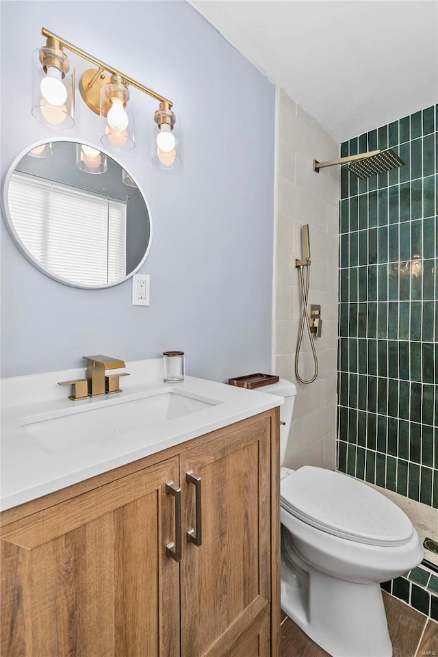 bathroom with hardwood / wood-style floors, tiled shower, vanity, and toilet