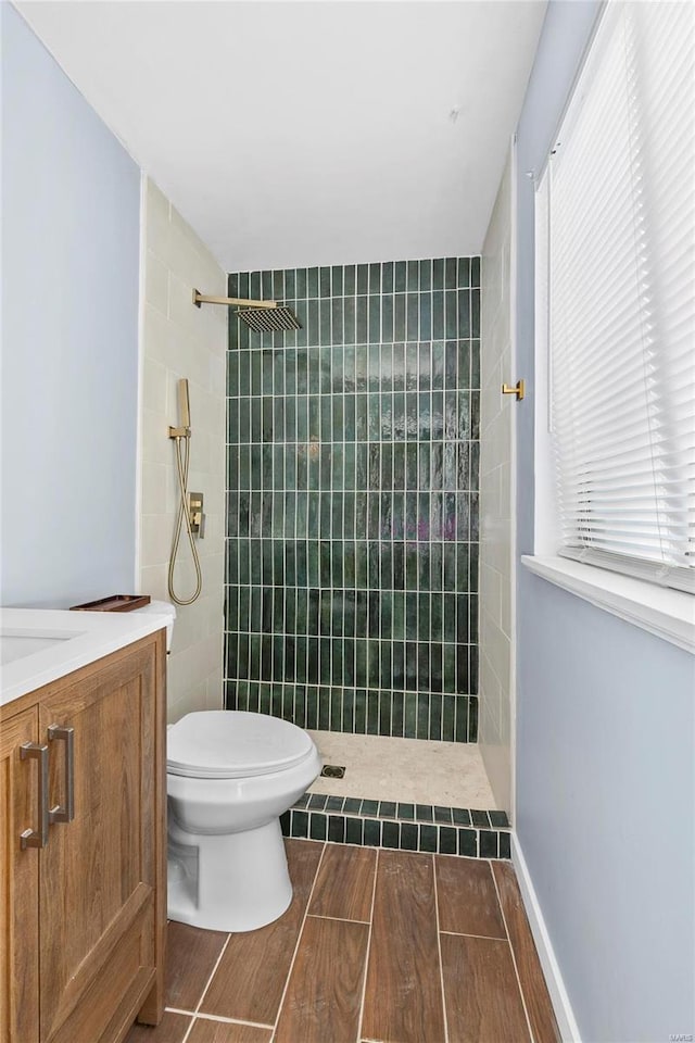 bathroom with vanity, toilet, and tiled shower