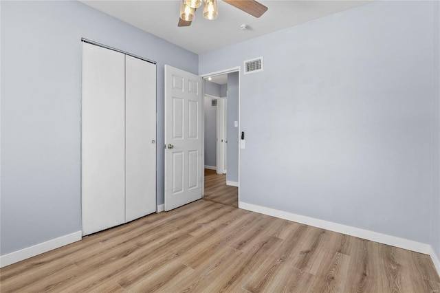 unfurnished bedroom featuring ceiling fan, a closet, and light wood-type flooring