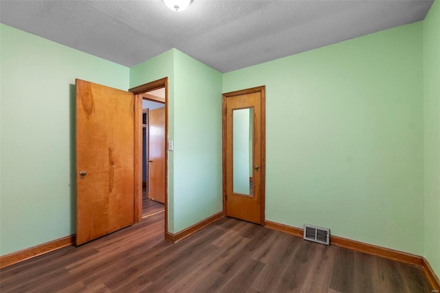 unfurnished bedroom featuring dark hardwood / wood-style flooring and a textured ceiling