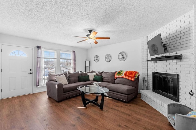 living room with ceiling fan, a textured ceiling, a fireplace, and dark hardwood / wood-style flooring