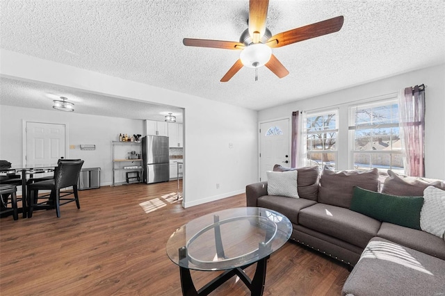 living room with ceiling fan, dark hardwood / wood-style flooring, and a textured ceiling