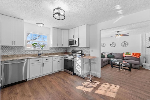 kitchen featuring sink, backsplash, stainless steel appliances, dark hardwood / wood-style floors, and white cabinets