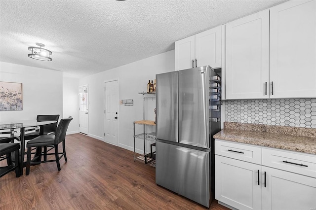 kitchen with tasteful backsplash, white cabinetry, stainless steel fridge, dark hardwood / wood-style flooring, and a textured ceiling