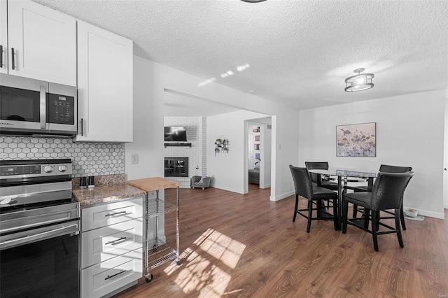 kitchen with backsplash, stainless steel appliances, light stone countertops, and white cabinets