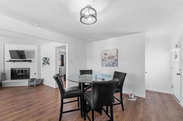 dining room featuring a fireplace, hardwood / wood-style floors, and a textured ceiling