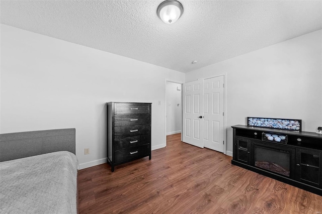 bedroom with dark hardwood / wood-style floors and a textured ceiling