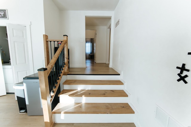 stairs with visible vents, baseboards, and wood finished floors