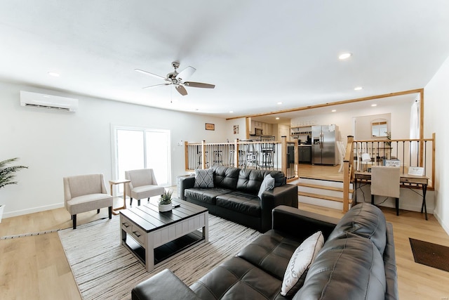 living room with baseboards, light wood finished floors, a wall unit AC, and recessed lighting