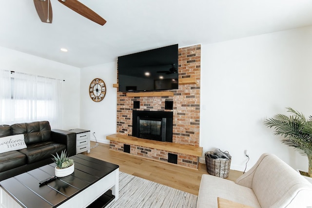 living room featuring baseboards, ceiling fan, wood finished floors, a brick fireplace, and recessed lighting