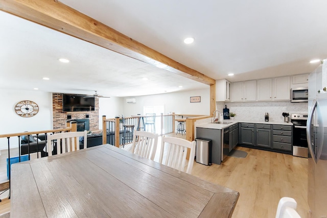 dining space with beam ceiling, recessed lighting, a brick fireplace, ceiling fan, and light wood-type flooring