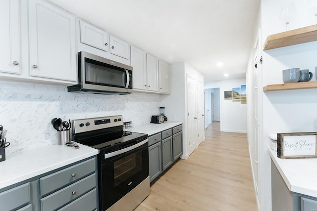 kitchen with gray cabinetry, light countertops, appliances with stainless steel finishes, open shelves, and tasteful backsplash