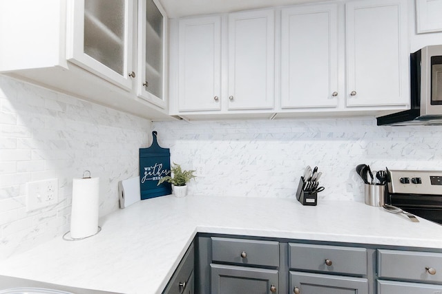 kitchen featuring glass insert cabinets, appliances with stainless steel finishes, light countertops, and gray cabinetry