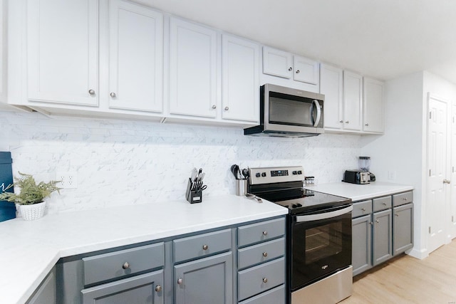 kitchen featuring light countertops, stainless steel appliances, decorative backsplash, and gray cabinetry