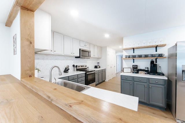 kitchen with open shelves, tasteful backsplash, gray cabinetry, appliances with stainless steel finishes, and a sink