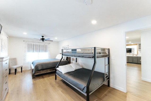 bedroom with baseboards, light wood-style flooring, ceiling fan, a sink, and recessed lighting