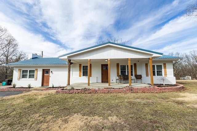 view of front of home with brick siding, a chimney, a front yard, a standing seam roof, and metal roof