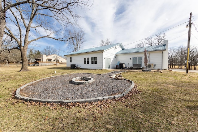 rear view of house featuring a yard, a chimney, a patio, an outdoor fire pit, and metal roof