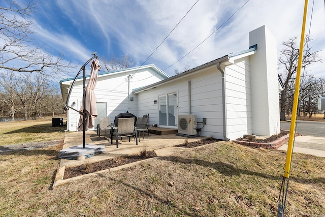 rear view of property with central AC, a patio area, a yard, ac unit, and a chimney