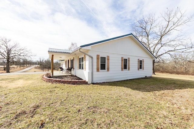 view of side of home with a yard and a patio