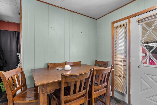 dining space with ornamental molding and wood walls