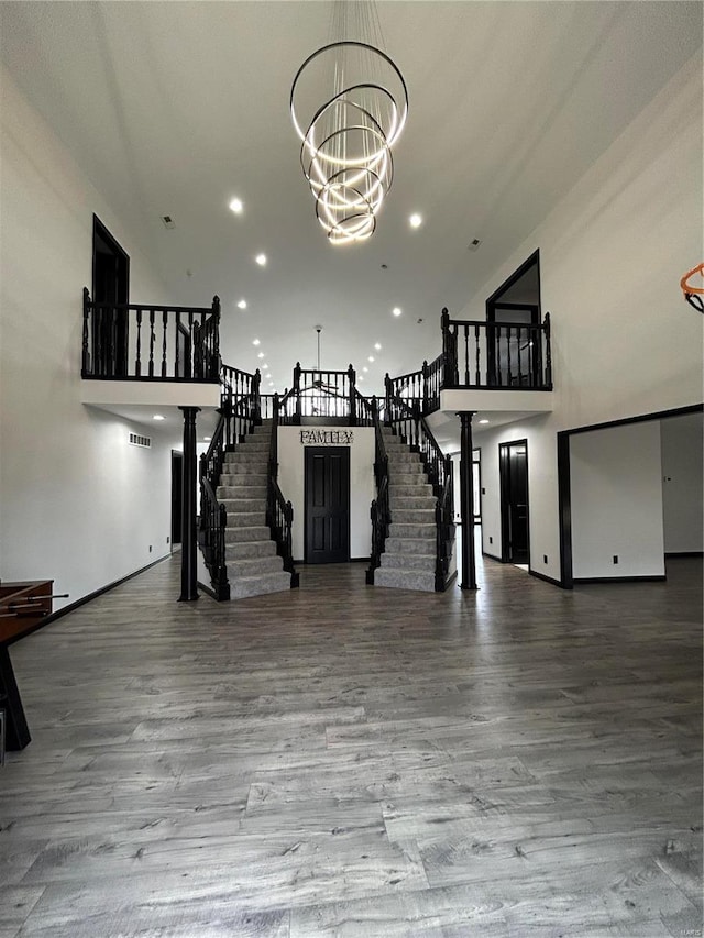 interior space with a chandelier, stairway, a towering ceiling, and wood finished floors